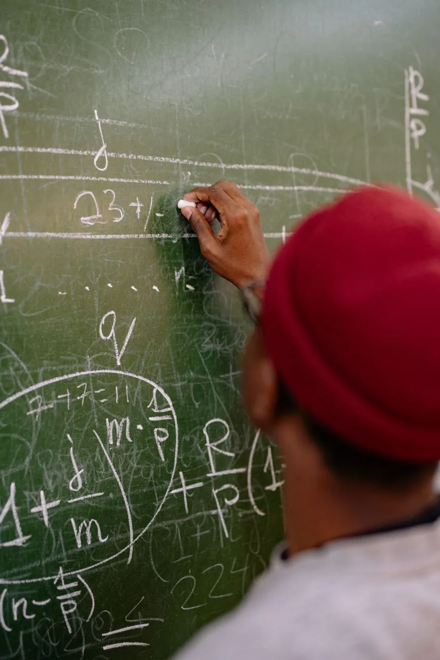 An instructor writing probability equations in chalk on a dark green board